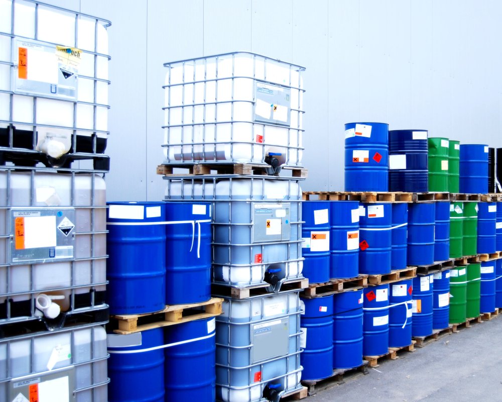 A group of blue and green barrels on a warehouse floor.